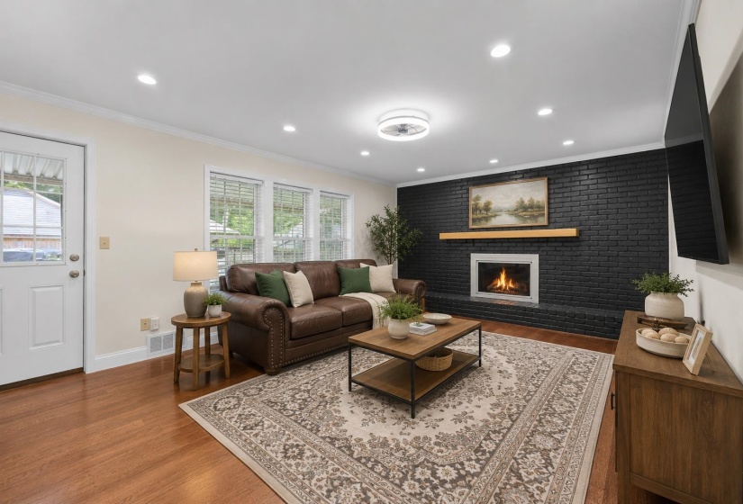 Beautifully updated great room showcasing a dramatic painted brick fireplace, recessed lighting, and rich hardwood-style flooring. Virtually staged to highlight the spacious layout, creating the perfect setting for relaxing evenings and entertaining.