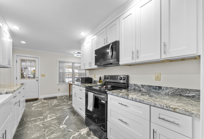 Renovated kitchen showcases abundant cabinet storage, granite countertops, farmhouse sink, and modern finishes designed for both function and style.
