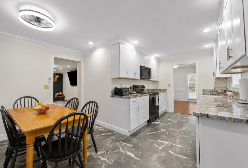 Beautifully updated kitchen featuring white shaker cabinetry, granite countertops, tile flooring, and an adjoining breakfast area for everyday convenience.