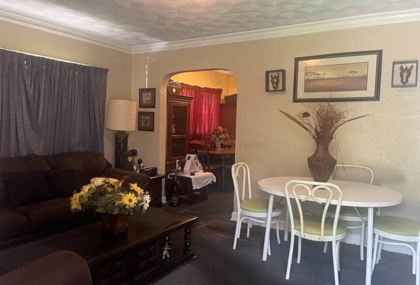 Living area featuring crown molding and an arched doorway