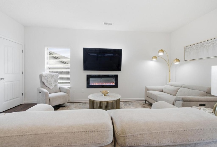 Bright living space featuring an electric fireplace and mounted television