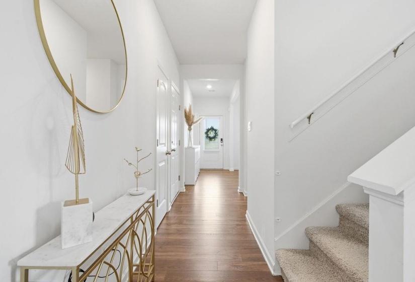 Entryway featuring wood-finish flooring, white walls, and a carpeted staircase