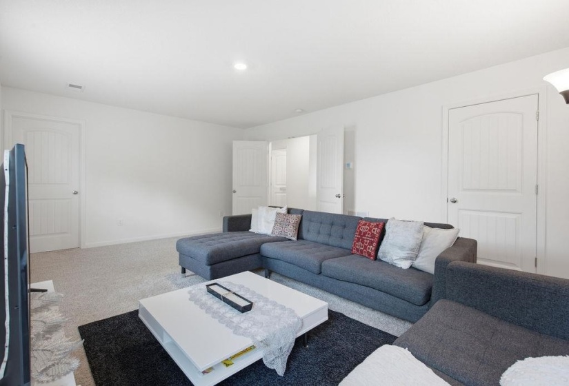 Spacious carpeted room featuring bright white walls, recessed lighting, and white paneled doors with arch top detailing