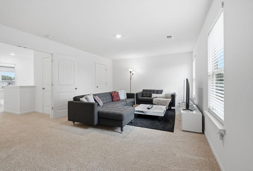 Carpeted living area featuring white walls, white trim, and recessed lighting