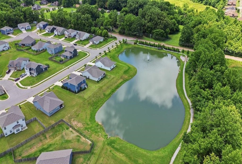 Neighborhood with a central pond featuring a fountain, surrounded by manicured green spaces and paved pathways