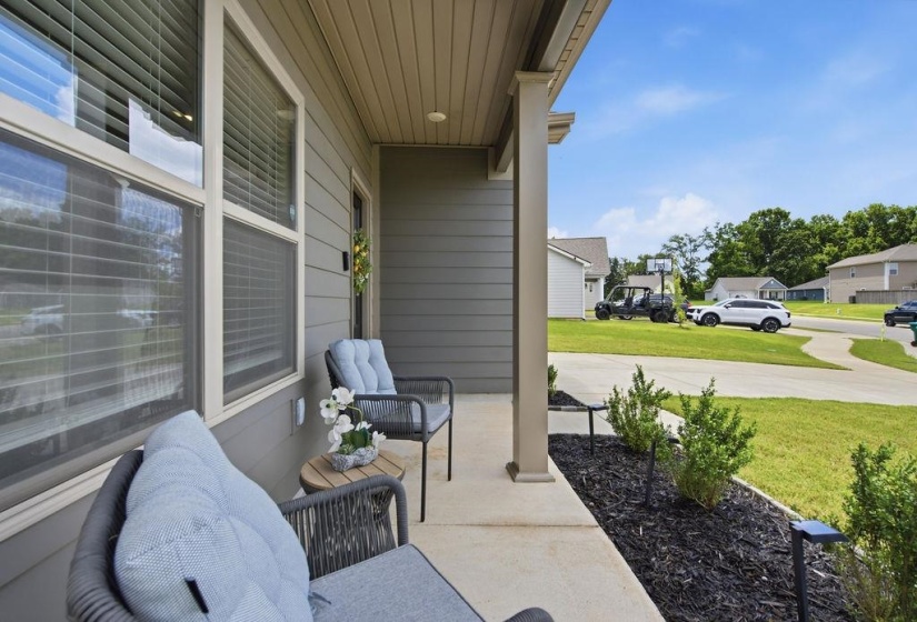 Covered front porch featuring a concrete pad, a siding exterior, and a landscaped bed with dark mulch and low-lying shrubs