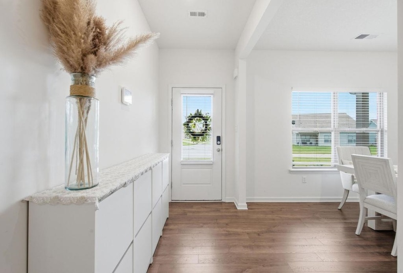 Open concept entry with wood-finish flooring extending into the dining area