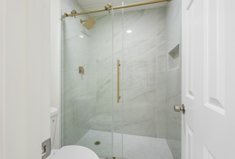 Spa-inspired walk-in shower with floor-to-ceiling tile, frameless glass enclosure, built-in niche, and elegant finishes that elevate the entire primary suite.