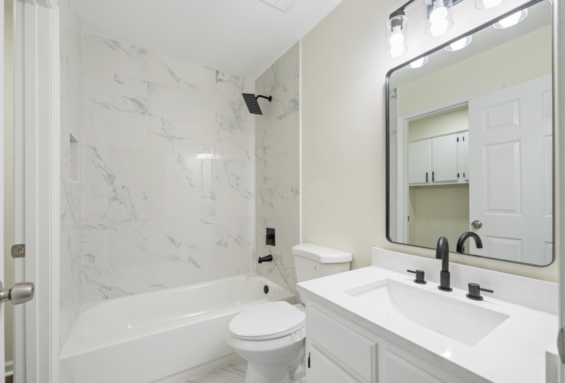 Renovated bathroom featuring a new vanity, updated fixtures, designer tile surround, new bathtub, and a fresh modern look.