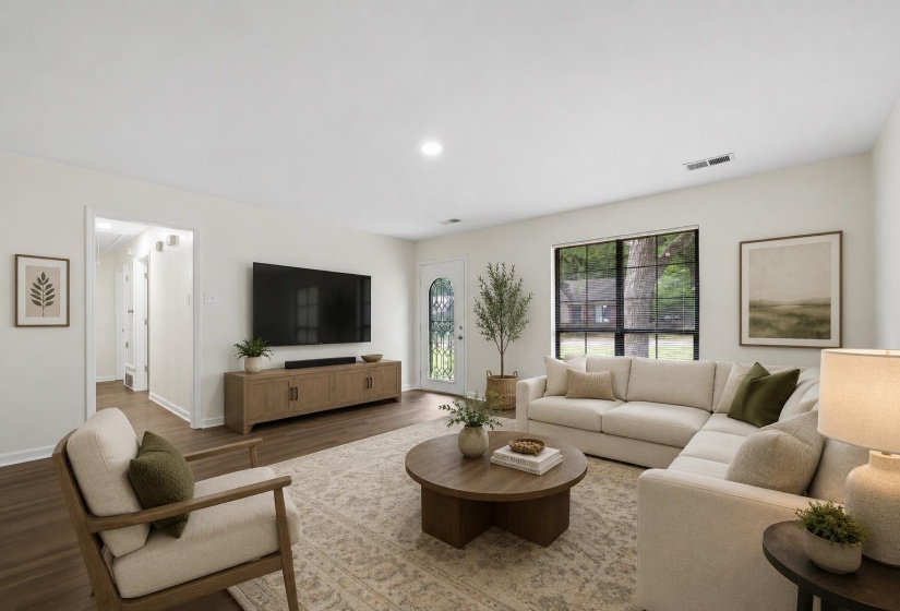 Spacious great room with updated wood laminate flooring, smooth ceilings, fresh paint, and large windows that fill the space with natural light. This photo has been virtually staged.