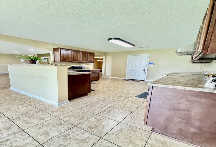 Kitchen featuring granite-style countertops, wood cabinetry, tile flooring, and a luminous ceiling fixture