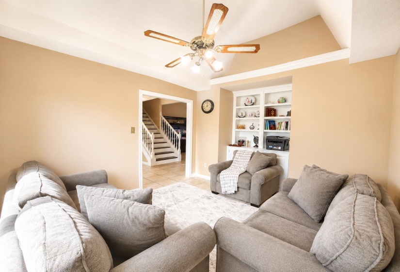 Living area with vaulted ceiling, crown molding, and a built-in shelving unit