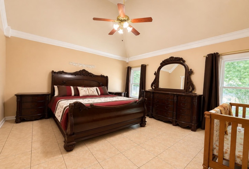 Spacious room featuring vaulted ceilings, crown molding, and neutral wall tones