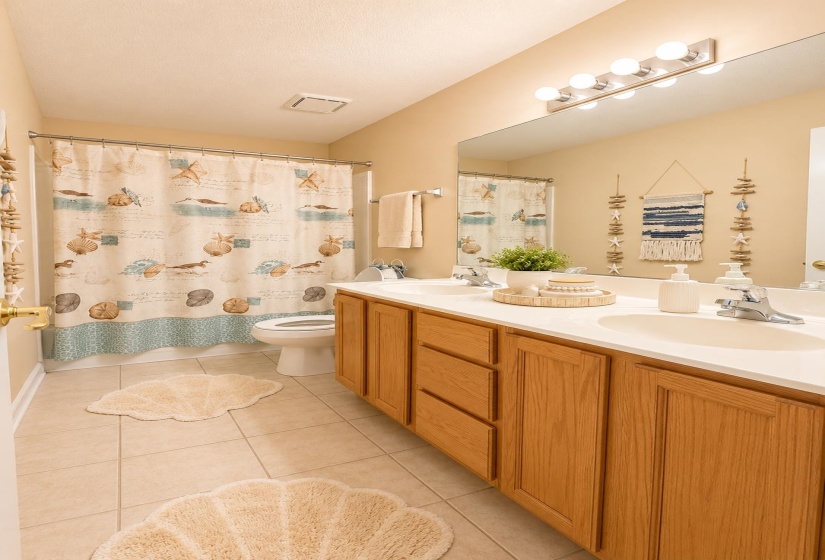 Dual vanity with wood-finish cabinetry, integrated sinks, and a single large mirror