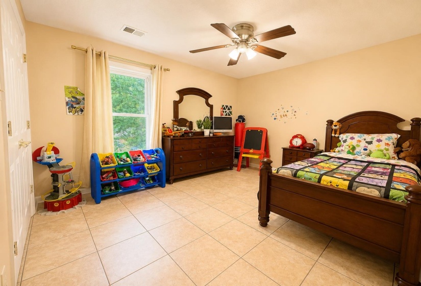 Spacious room featuring tile flooring, a large window with natural light, a ceiling fan with integrated lighting, and neutral wall tones