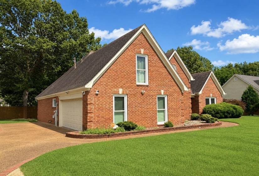 Brick exterior featuring multiple gables, white window casings, and a dark shingle roof