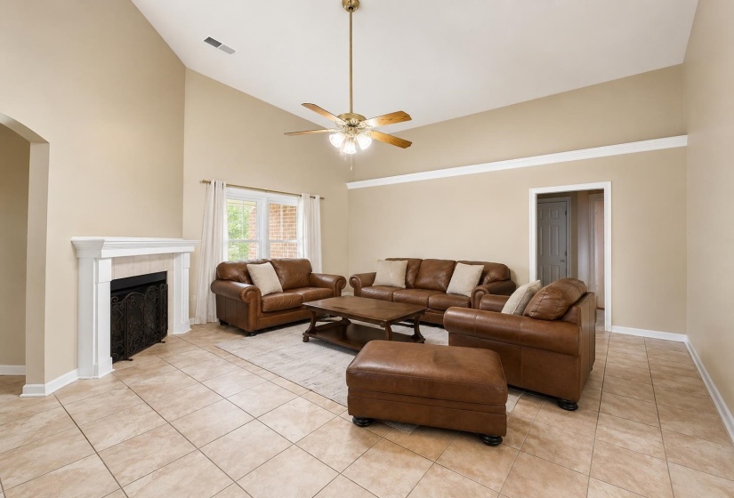 Spacious living area featuring a vaulted ceiling and a ceiling fan with integrated lighting