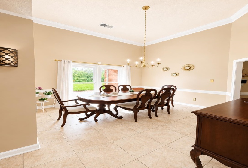 Spacious room featuring vaulted ceilings, crown molding, chair rail molding, and large format tile flooring