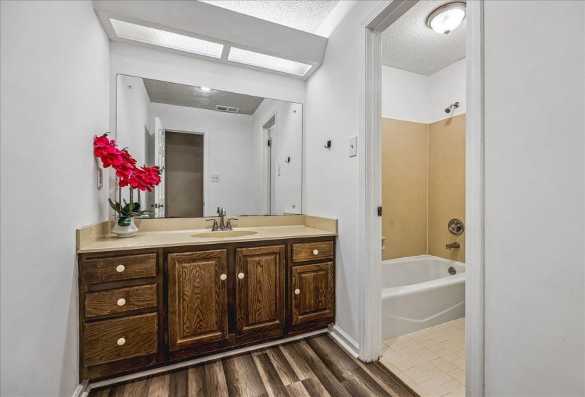 Bathroom vanity featuring a wood-finish cabinet, integrated sink, and expansive wall mirror