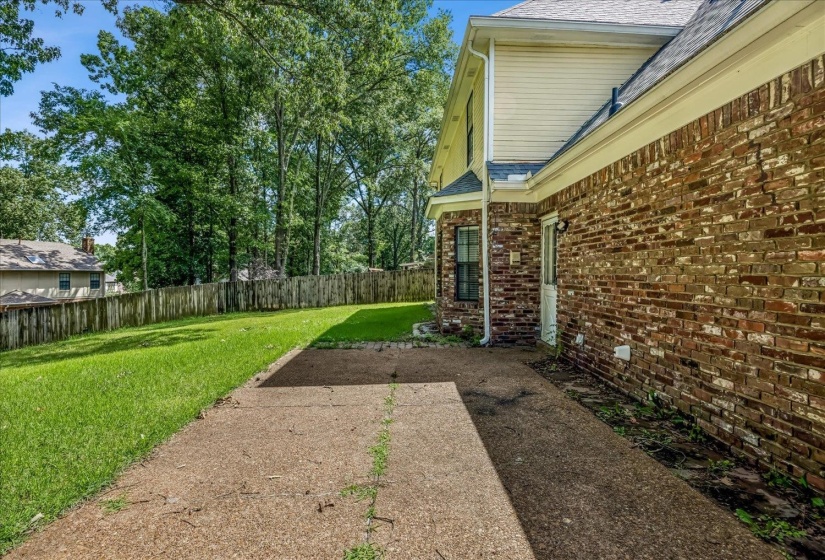 Expansive grass lawn with mature trees and a wood fence