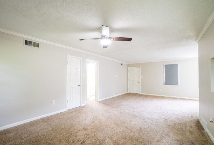 Spacious room featuring neutral carpeting, light-toned walls, and white trim