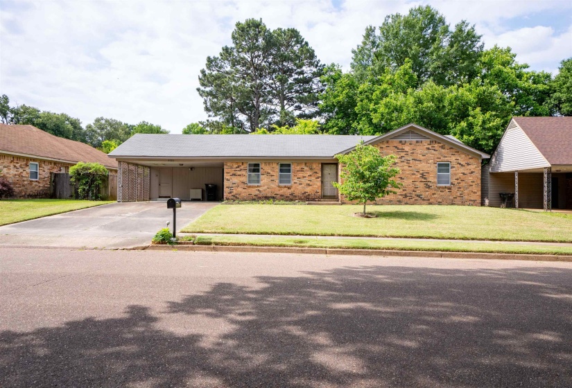 Brick exterior residence featuring a front lawn and paved driveway