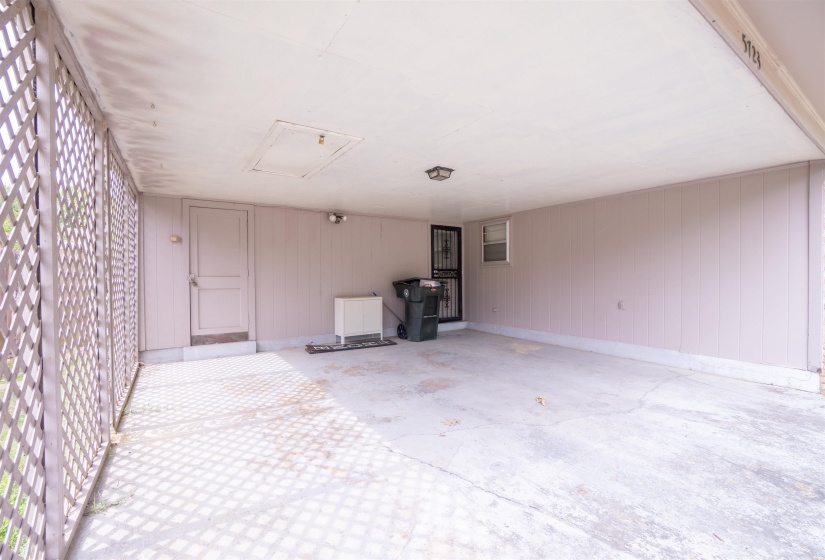 Covered carport with concrete flooring, complete with a lattice-style enclosure and a flush-mount overhead light fixture