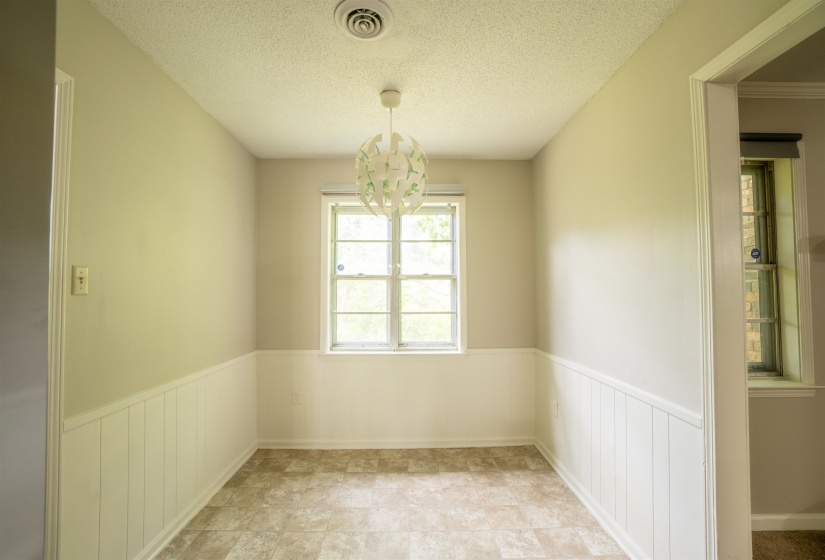 Compact room featuring neutral painted walls with beadboard paneling, tiled flooring, and a modern spherical light fixture