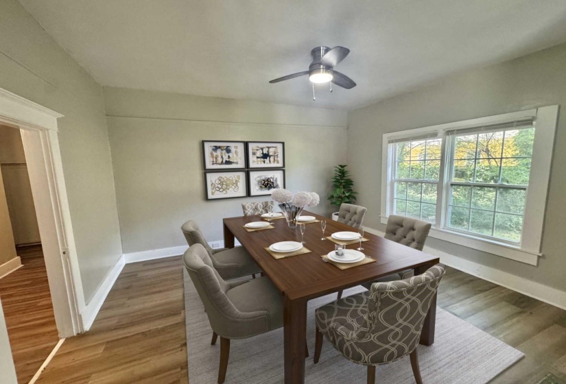 Spacious room featuring wood-finish flooring, a contemporary ceiling fan, and large windows with white trim