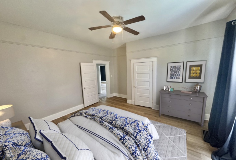 Interior space featuring wood-finish flooring, a ceiling fan with integrated lighting, white trim and baseboards, and a paneled interior door