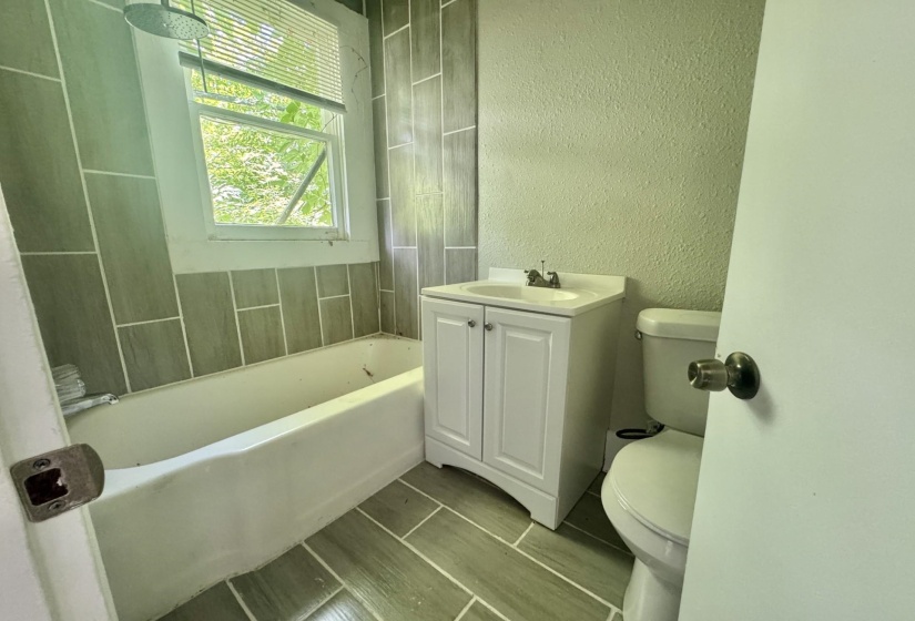 Bathroom featuring a white vanity with integrated sink, a white toilet, and a white bathtub with a shower head