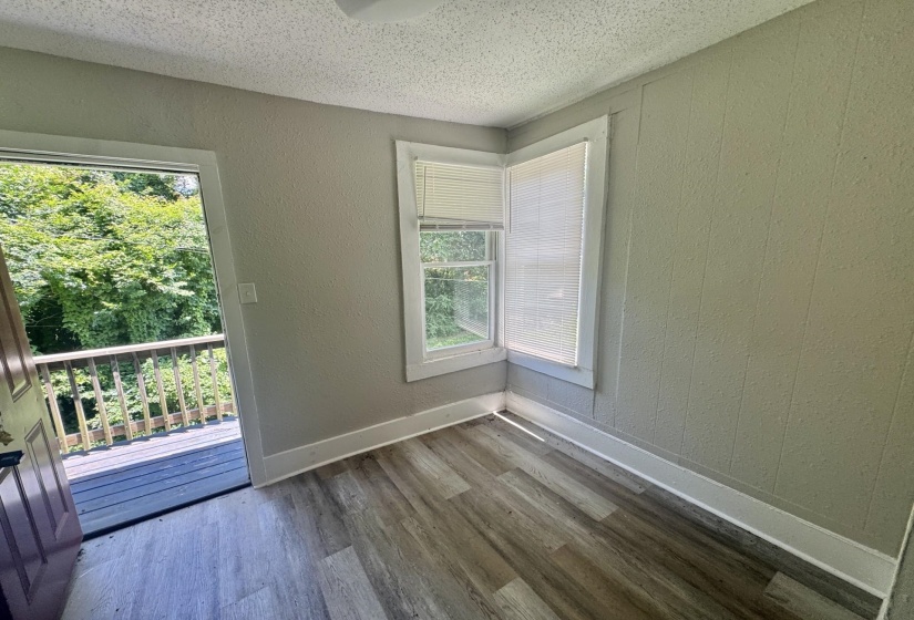 Room featuring wood-finish flooring, light grey walls, and white trim