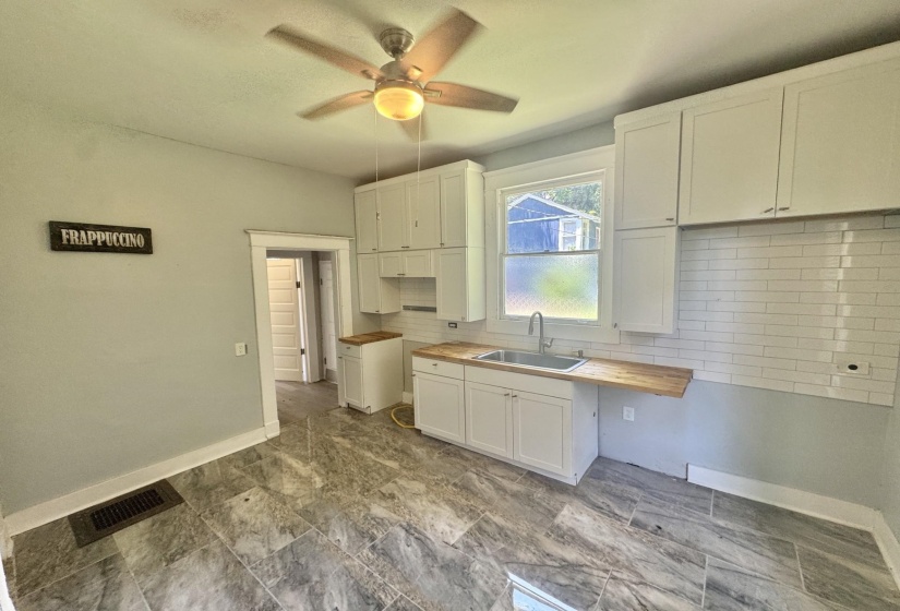Kitchen featuring white shaker-style cabinetry, wood-finish countertops, subway tile backsplash, and a stainless steel sink with a gooseneck faucet