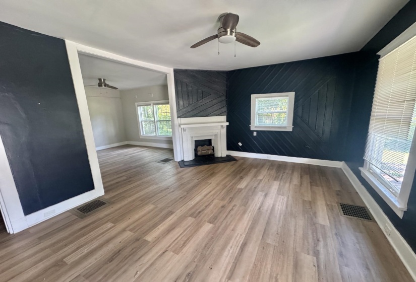 Living area featuring wood-finish flooring and a decorative fireplace with a white mantel and black hearth