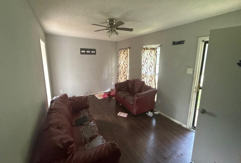 Spacious interior featuring wood-finish flooring, light grey painted walls, and a ceiling fan