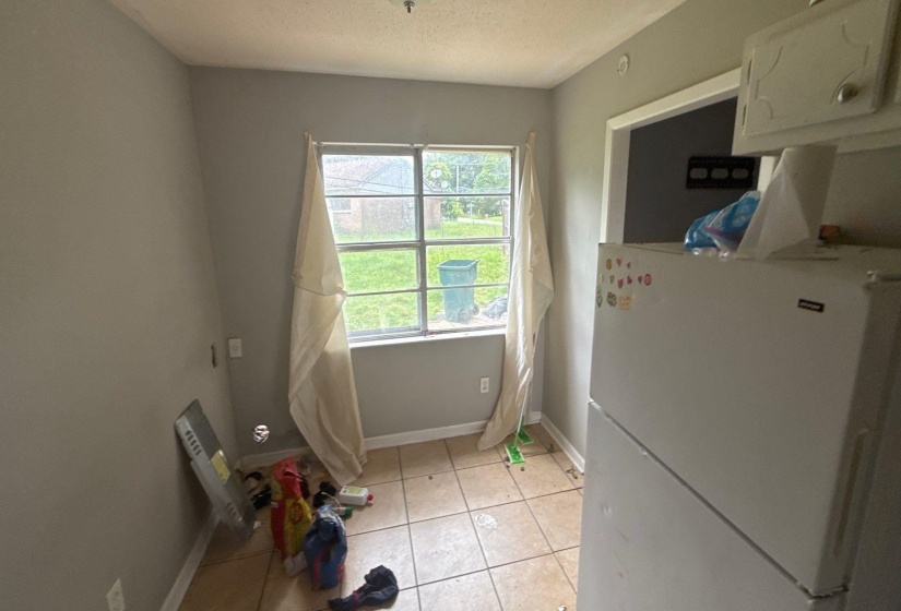 Kitchen area featuring a window with exterior views, tile flooring, light gray wall paint, and white trim