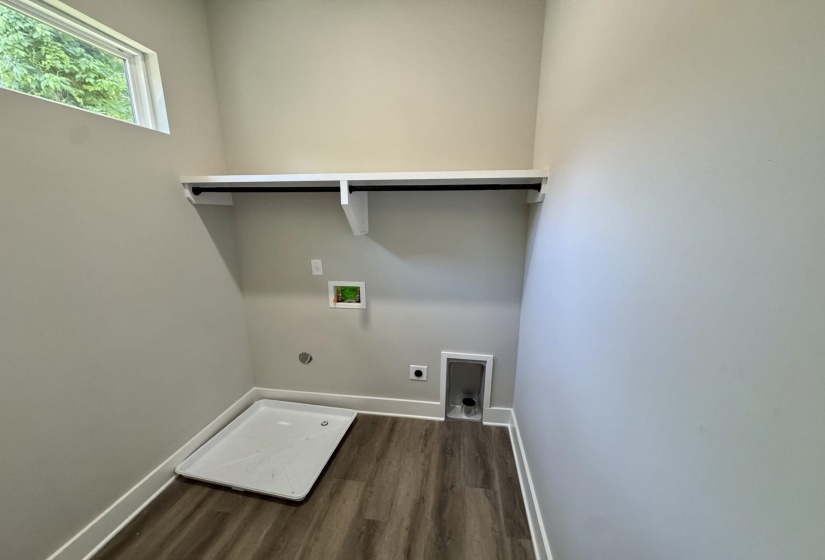 Dedicated utility space featuring wood-finish flooring, a high-mounted window, a built-in shelf with a hanging rod, and a utility basin