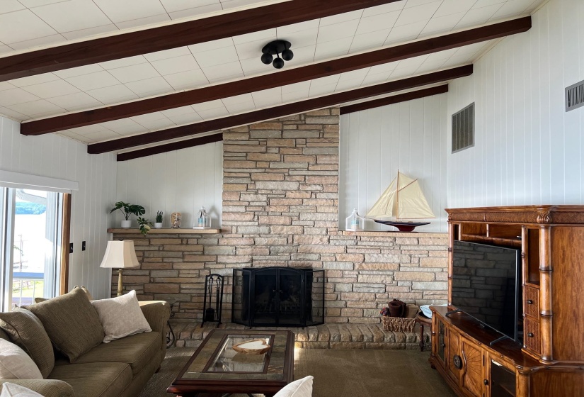 Spacious living area featuring a floor-to-ceiling stone fireplace with a hearth and a black fire screen