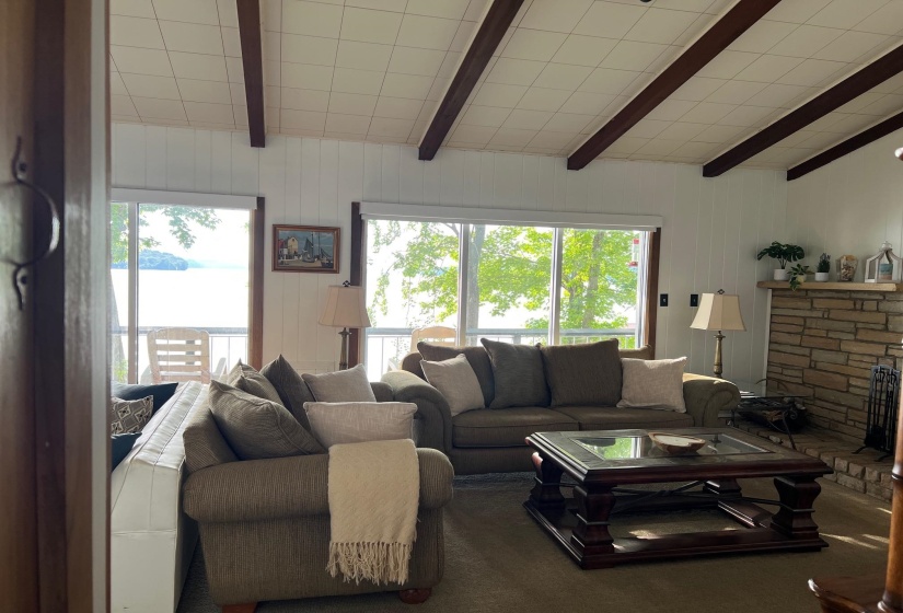 Living space featuring exposed ceiling beams and a stone-clad fireplace