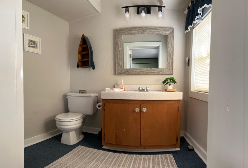 Bathroom featuring a single vanity with wood cabinetry, a light-toned countertop, and a framed mirror