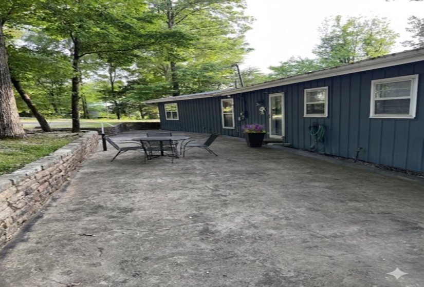 Expansive exterior patio featuring a decorative stone retaining wall and direct access to the home