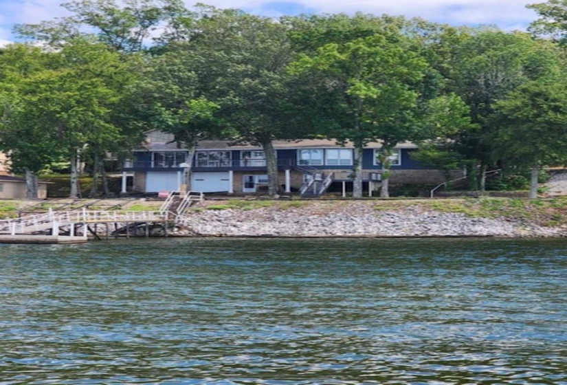 Waterfront property featuring a private dock, boathouse with two bay doors, and a multi-level deck