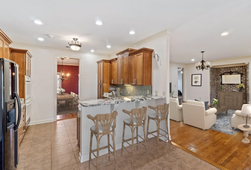 Kitchen with a chandelier, brown cabinets, a breakfast bar area, hanging light fixtures, and crown molding