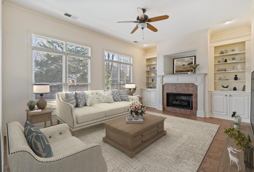 Living room featuring built in shelves, a tile fireplace, ornamental molding, and ceiling fan