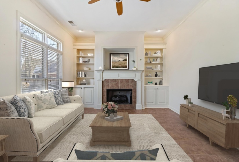 Tiled living room with crown molding, built in features, a ceiling fan, and a tiled fireplace