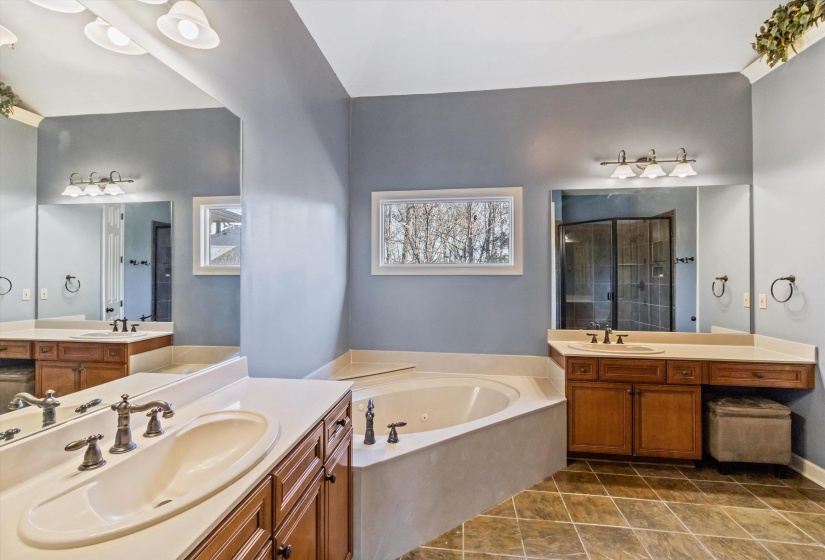 Bathroom with two vanities, a garden tub, and a stall shower