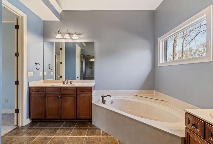Full bath featuring vanity, a jetted tub, and a stall shower