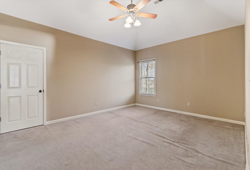 Empty room featuring carpet floors, lofted ceiling, and a ceiling fan
