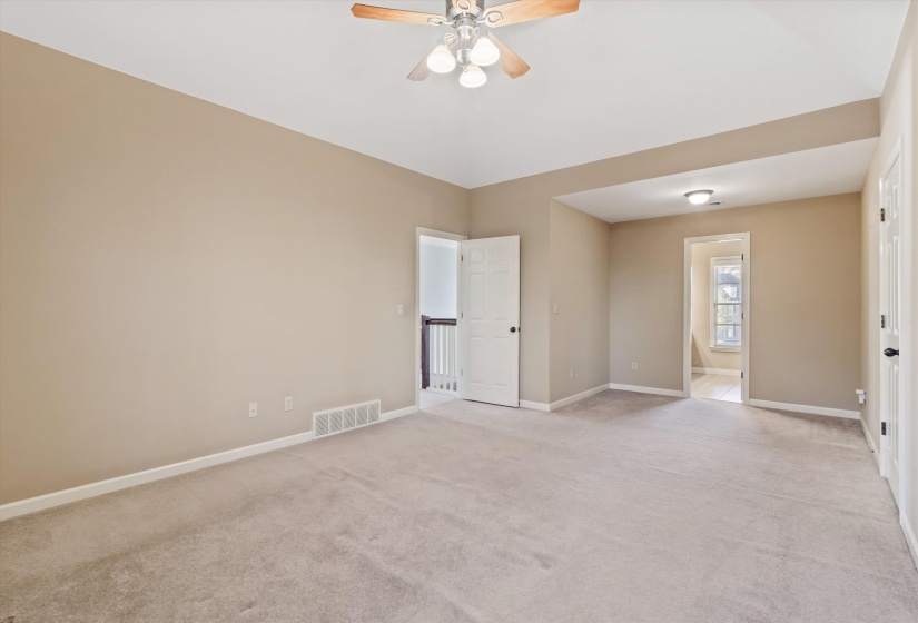Empty room with light colored carpet and ceiling fan