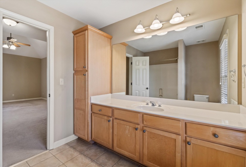 Bathroom featuring light carpet, vanity, a shower, light tile patterned flooring, and ceiling fan